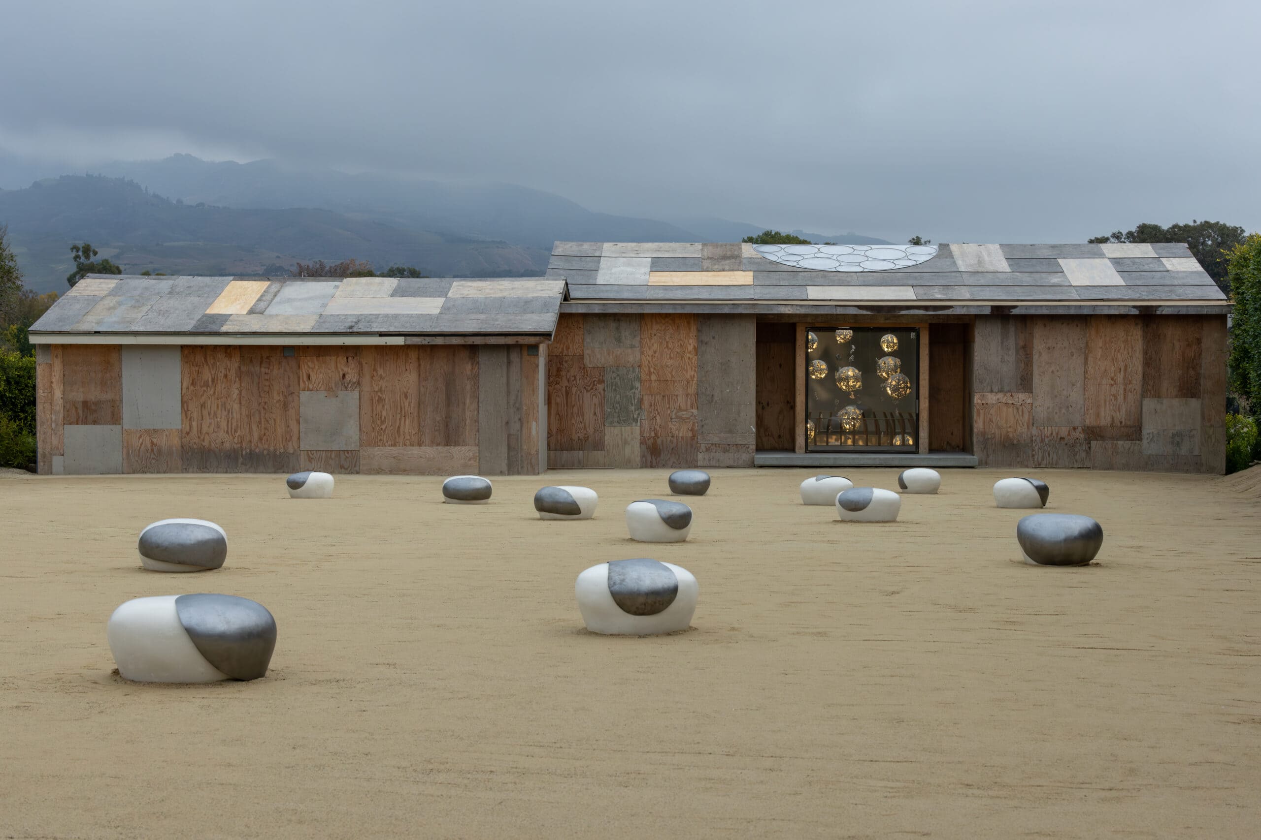 Dots art installation by Brigitte D'Annibale. Items in gray and white clustered on a sandy field