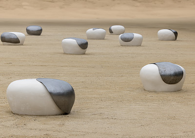 Dots art installation by Brigitte D'Annibale. Items in gray and white clustered on a sandy field